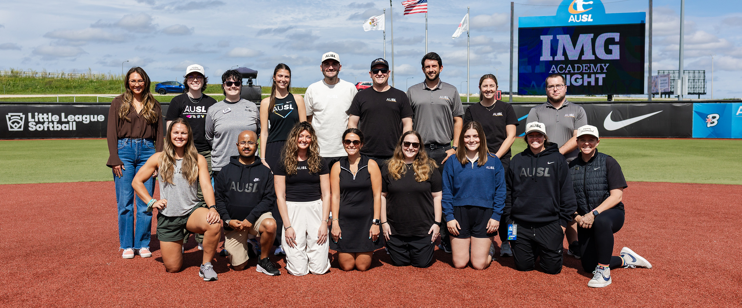 Group photo featuring seventeen Athletes Unlimited staff members smiling on the softball field
