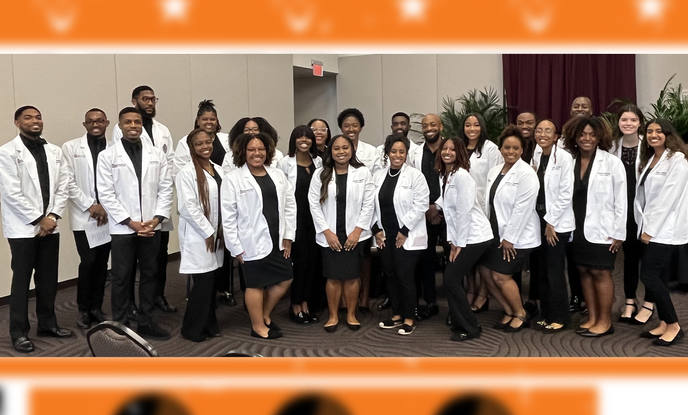 A large group choir in white lab coats smiling at the camera